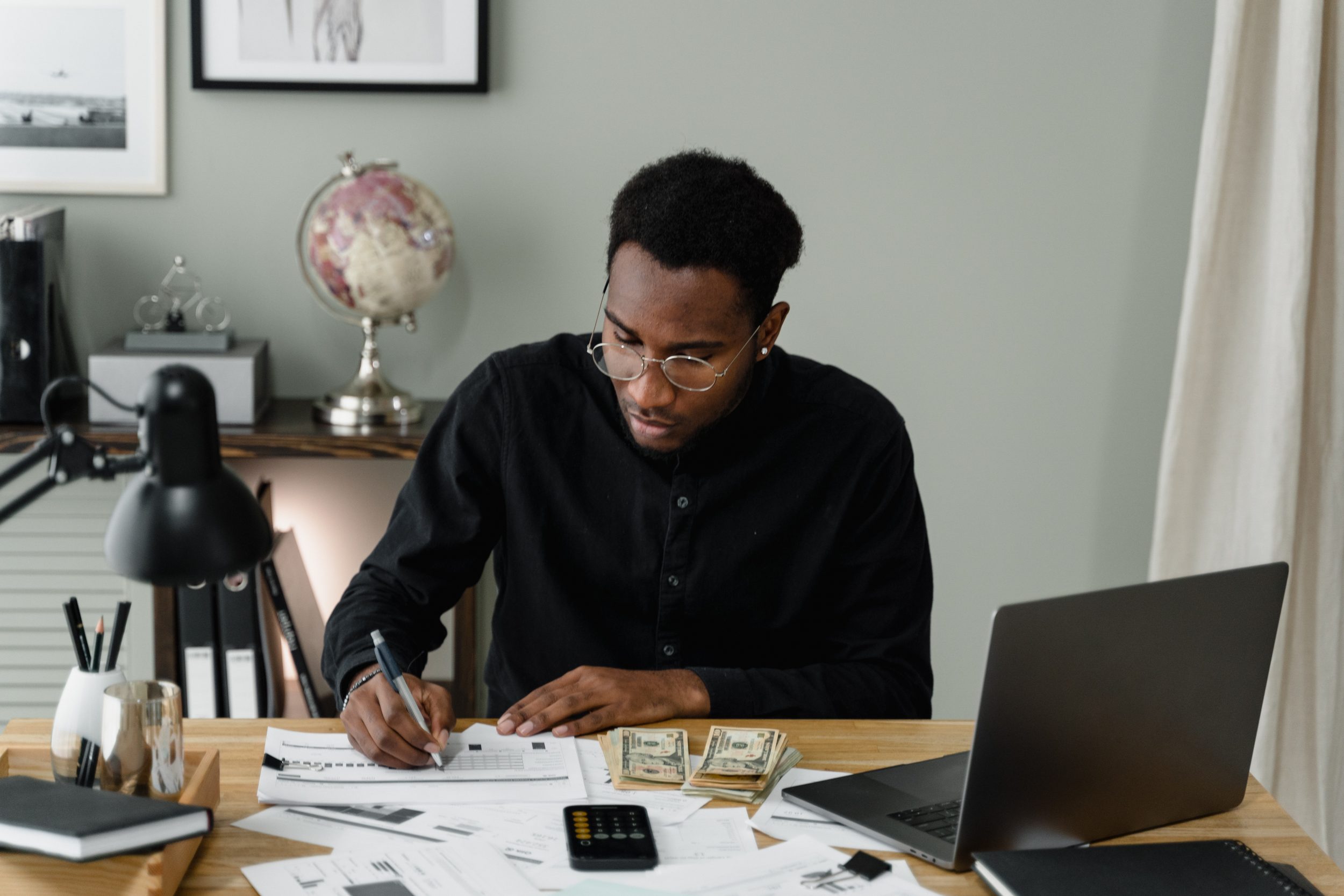 man working on desk with money and laptop